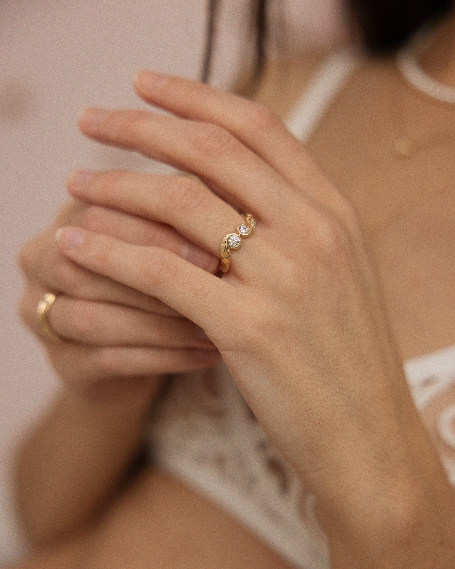 model i undertøj fra Liniere Lingerie med to organiske ringe i genanvendt guld. Ringene er formgivet organisk og blødt med diamanter der glimter.