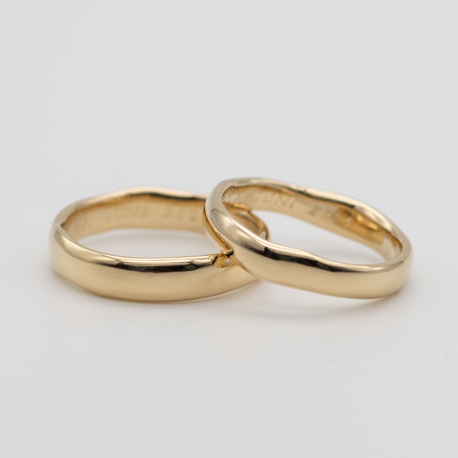 to vielsesringe i enkelt og organisk design. ringene er i massivt guld og ligger på hvid baggrund
