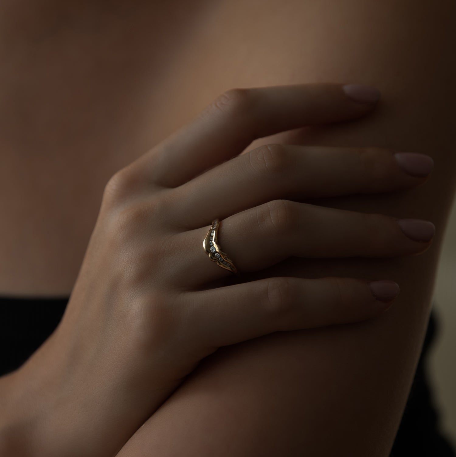 Model hånd med organisk formgivet guld ring med diamanter på række. sort top 