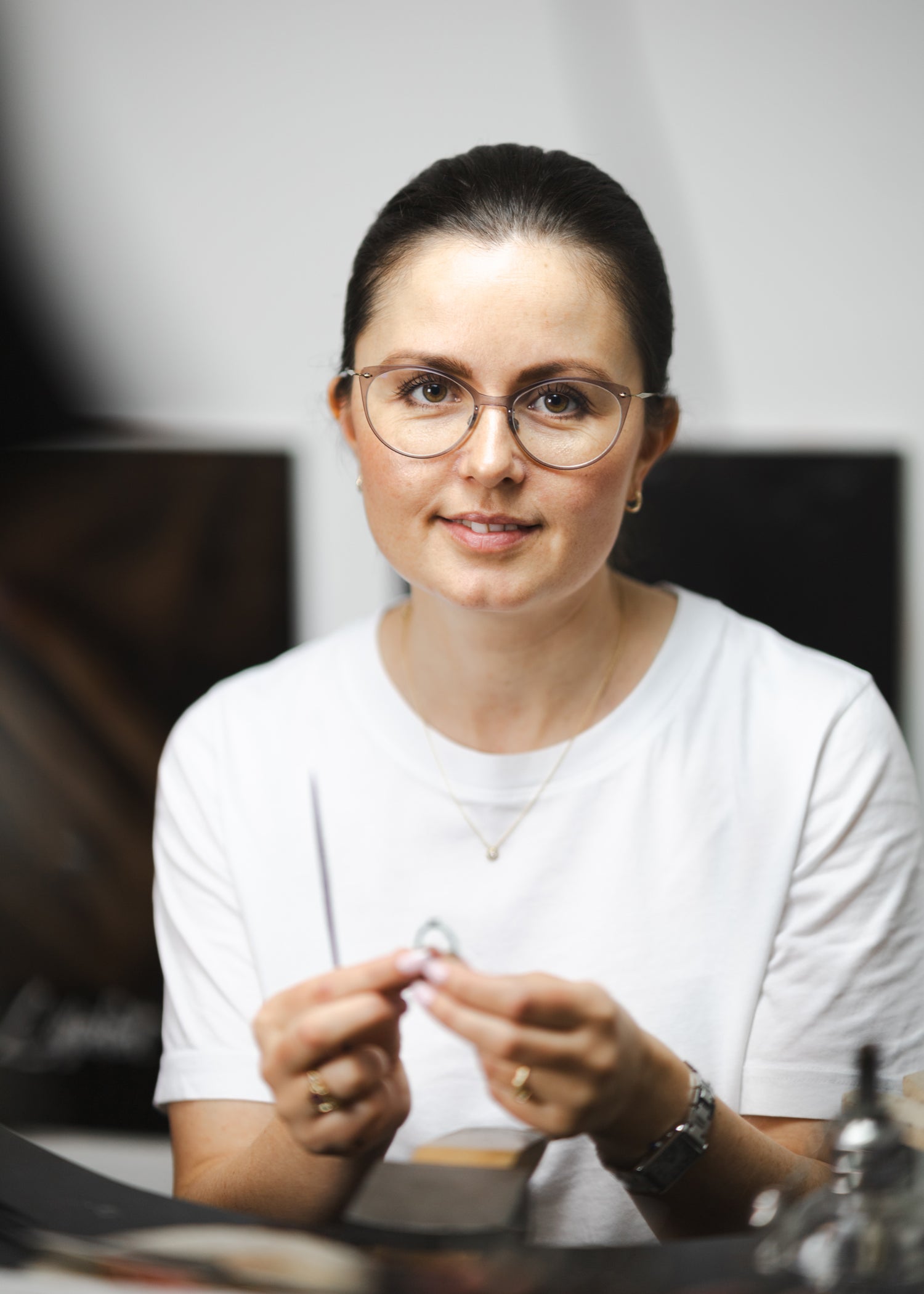 Billede af Michell Liljefelt i sit smykkeværksted der holder et nyt unika-smykke i hånden
