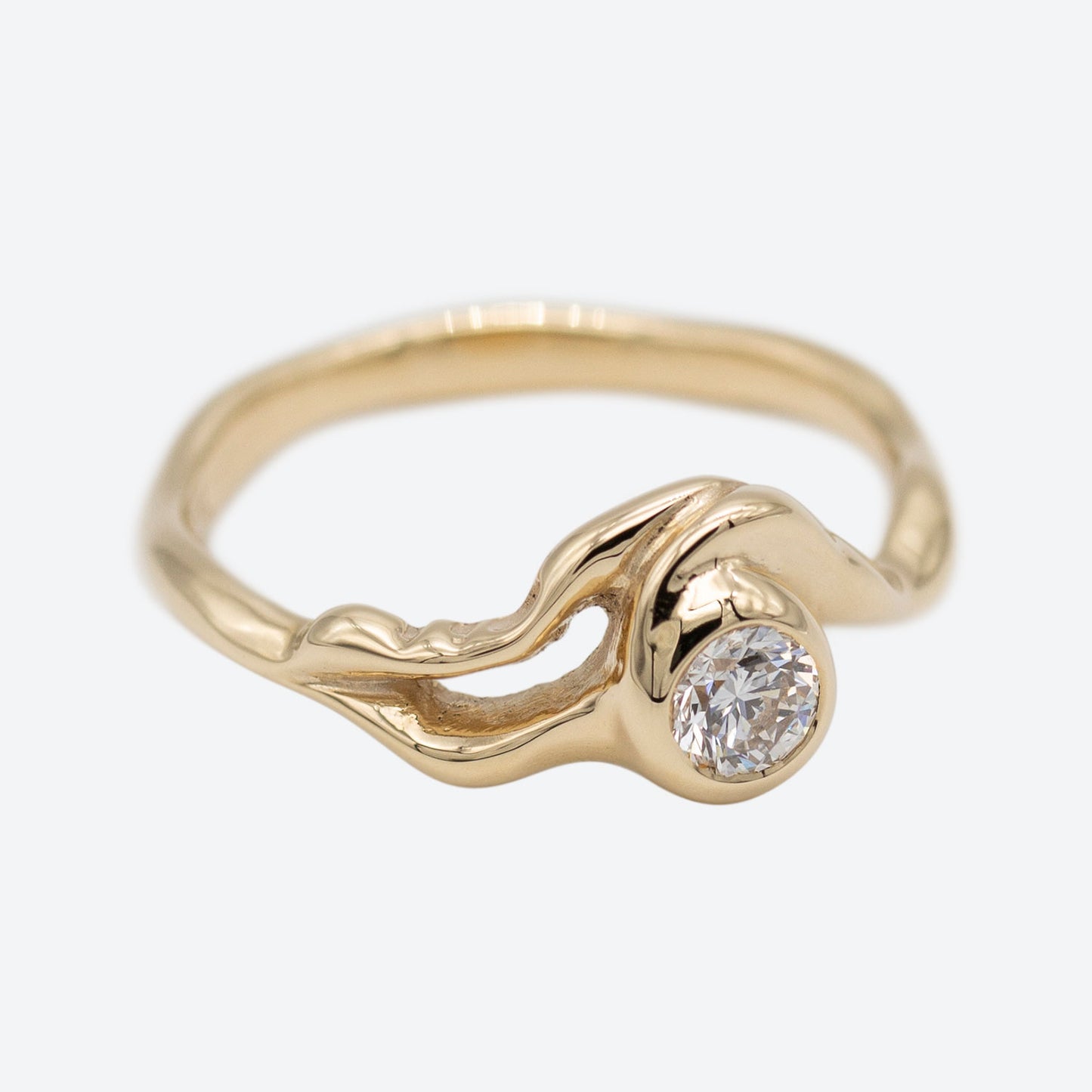 Organisk formgivet ring i guld med stor diamant placeret i centrum af ringen. Ud fra diamanten forgrener formgivningen sig rundt i ring skiven. Set i perspektiv
