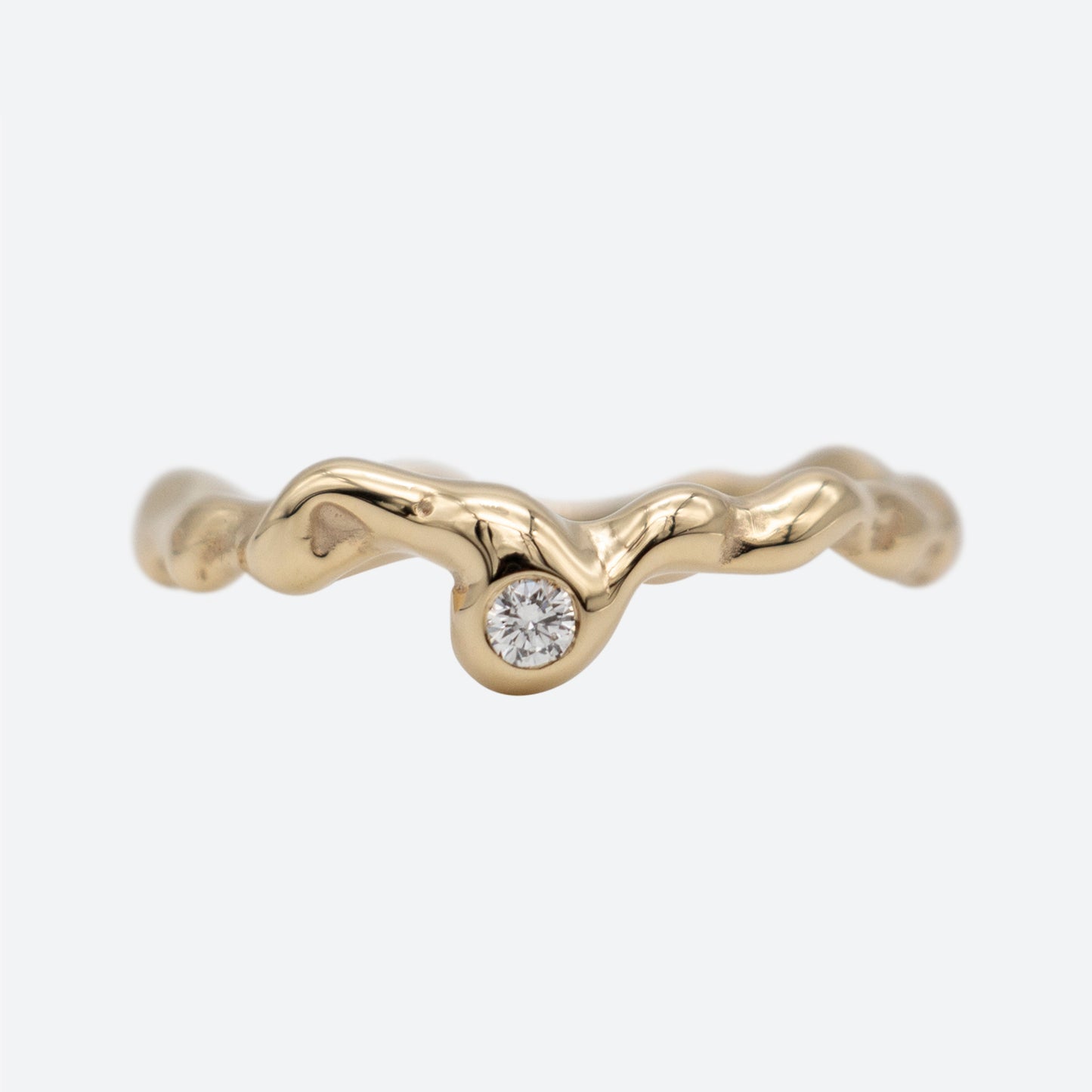 Organisk design ring i guld med en diamant på hvid baggrund. Design af Michell Liljefelt