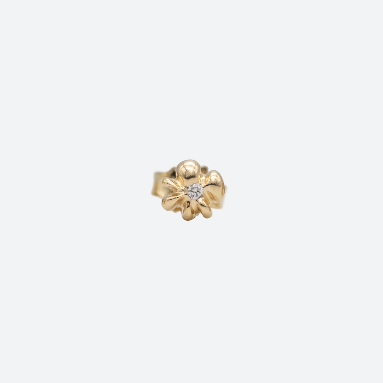 En ørestik i guld formet som en blomst med en diamant i midten på hvid baggrund